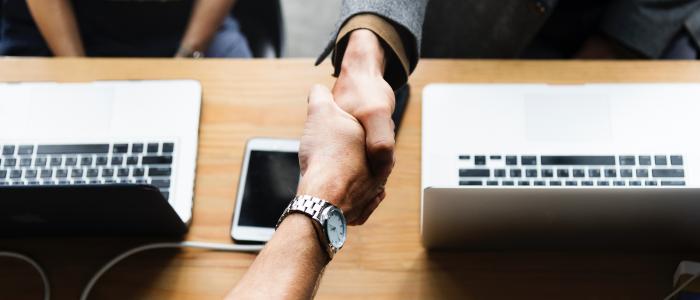 An image of business people shaking hands over a desk